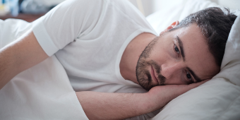 Foto: Depressiver Mann liegt im Bett