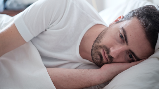 Foto: Depressiver Mann liegt im Bett